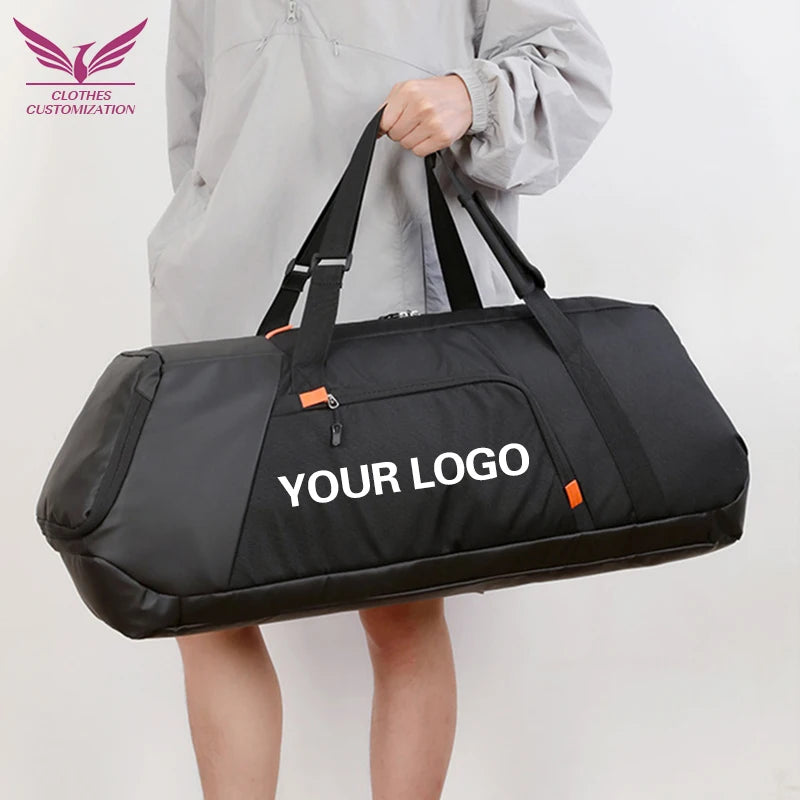 A person in a light gray jacket holds a large black duffel bag with white 'YOUR LOGO' text on the front. The bag has black handles, a zippered main compartment, and small orange accent tabs.