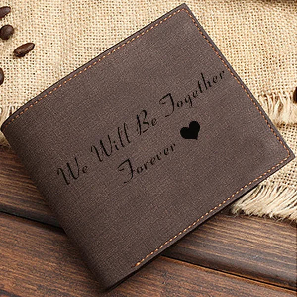 Brown leather wallet with 'We Will Be Together Forever' engraving on a wooden surface.