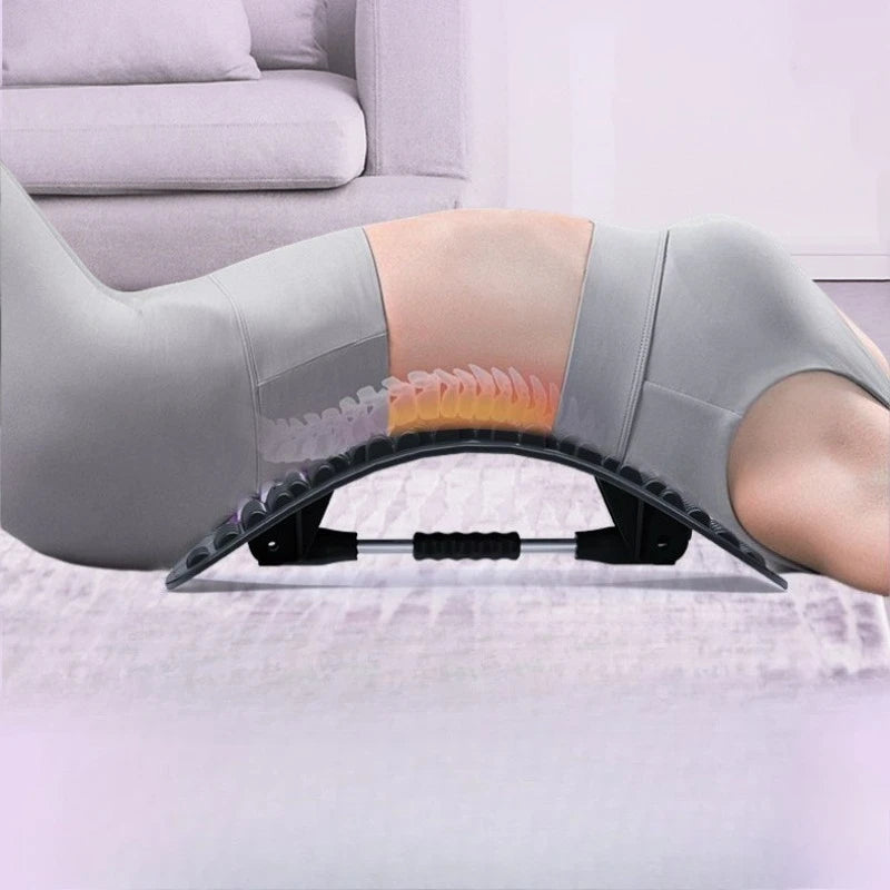 An abdominal exercise roller on a person's lower back, shown in use with a glowing heat overlay indicating massage or heat therapy. The person is wearing gray leggings, and a sofa is visible in the background.