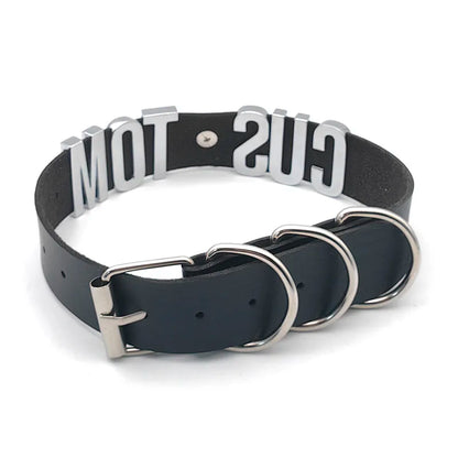 Black dog collar with metal rings and 'GUS' branding on a white background