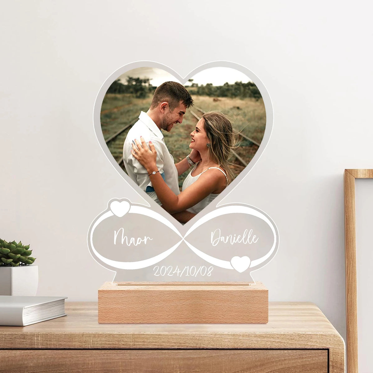 Heart-shaped photo frame with a couple's picture and personalized text on a wooden surface.