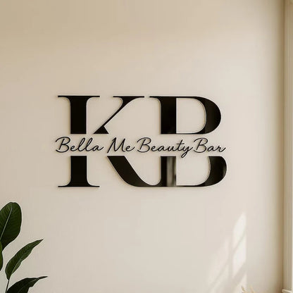 Decorative wall art with 'KB' initials and 'Bella Me Beauty Bar' text on a beige wall.