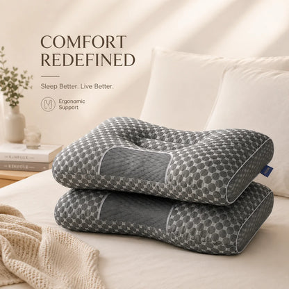 Two contoured neck pillows with a gray and white geometric pattern are stacked on a bed with white pillows and a beige blanket. Text on the left reads 'COMFORT REDEFINED' and 'Ergonomic Support'.