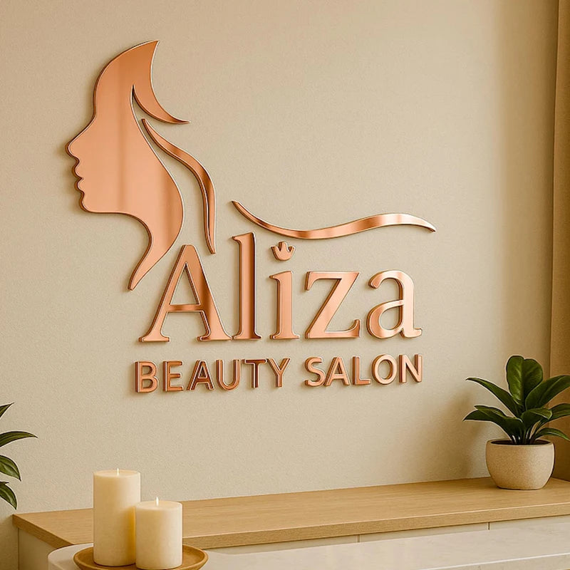 Rose gold metallic 3D wall art featuring a woman's profile silhouette, the name 'Aliza', and 'BEAUTY SALON' mounted on a beige wall above a wooden console table with candles and a potted plant.