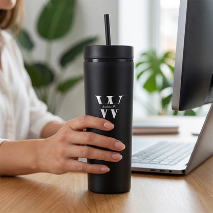 Person holding a black tumbler with a logo in an office setting