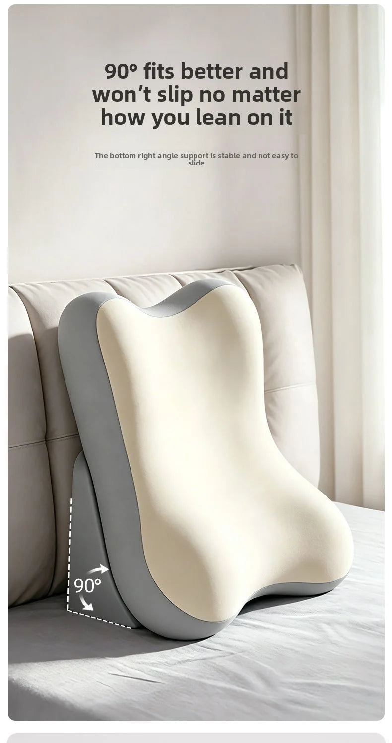 A curved neck pillow shown resting on a bed in a softly lit bedroom. The pillow has a cream-colored top section and a gray side section, with text above describing slip resistance and a diagram showing a 90-degree angle at the base.