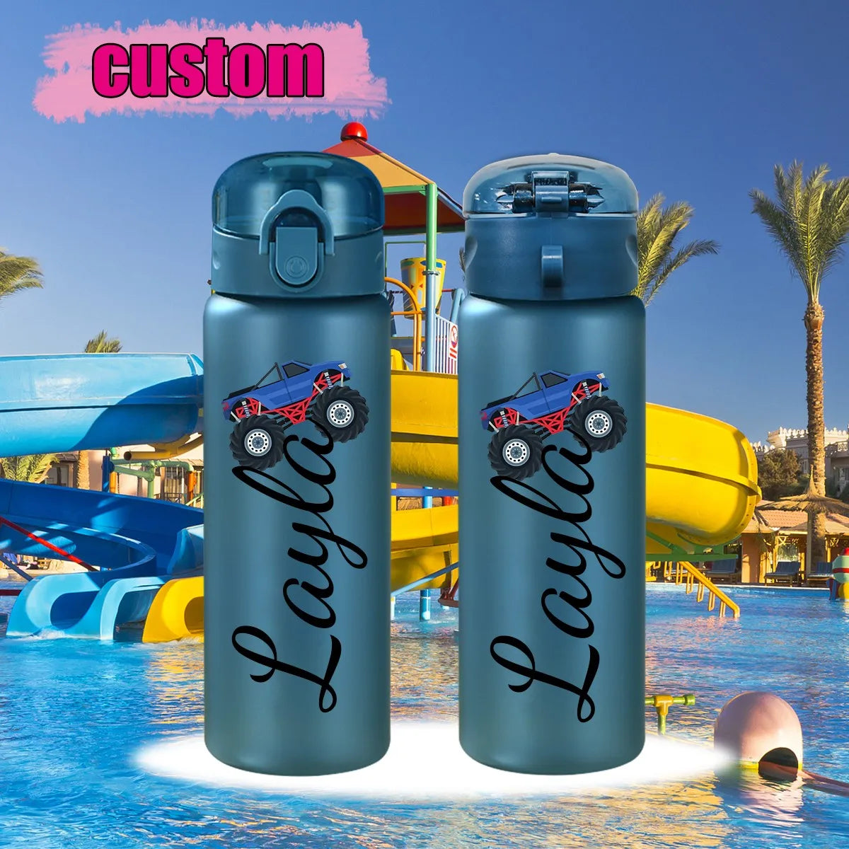 Two blue water bottles with a monster truck design and 'Layla' text in front of a pool and playground.