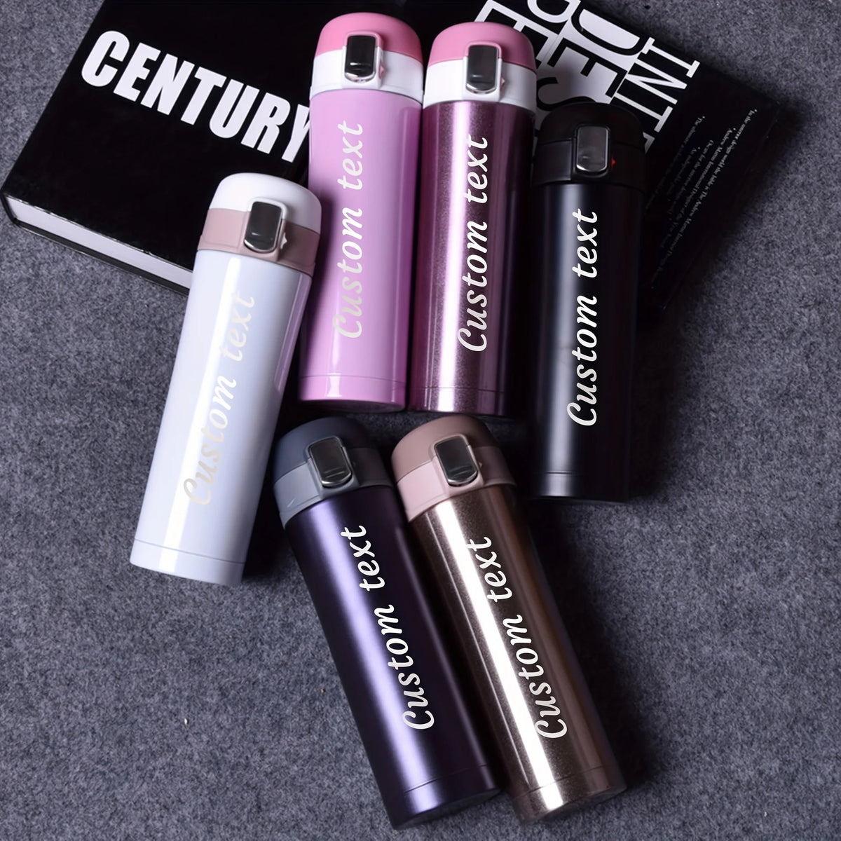 Set of personalized tumblers with 'Custom text' on a gray surface.