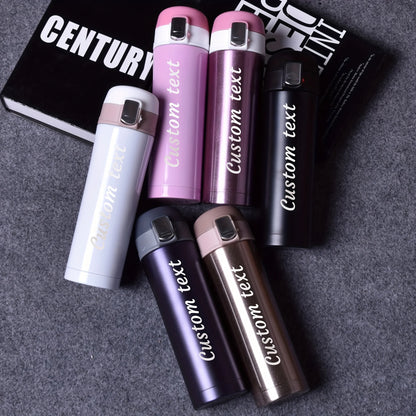 Set of personalized tumblers with 'Custom text' on a gray surface.