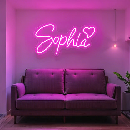 Neon sign with the name 'Sophia' above a purple sofa in a room with pink lighting.
