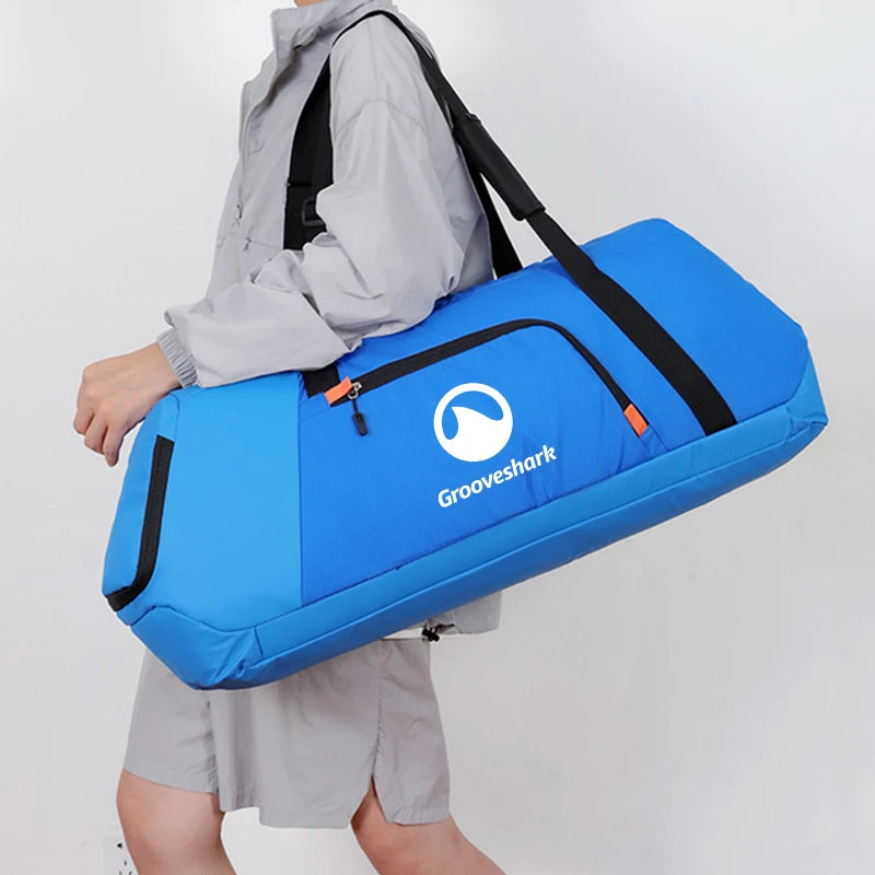 A person wearing a light gray jacket and shorts carries a large blue duffel bag with black straps and the Groovshark logo on a plain light gray background.