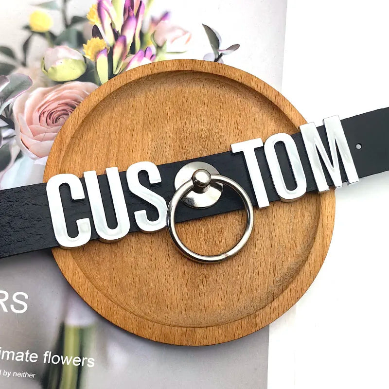 Wooden tray with a black belt labeled 'CUSTOM' on a blurred floral background